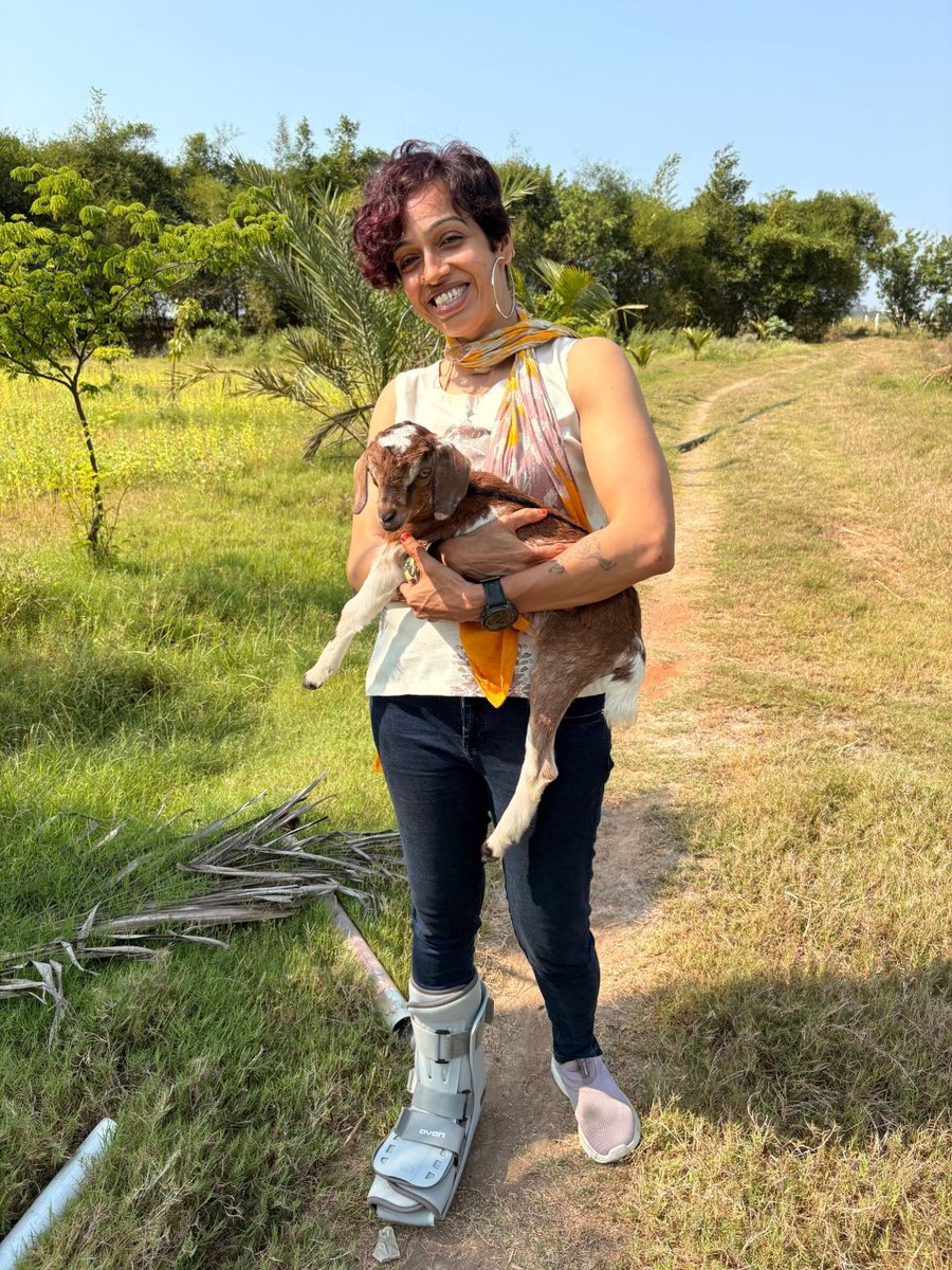 KP holding a goat in a field